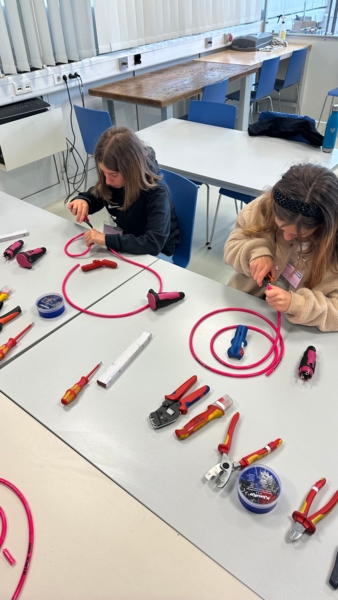 Girls'Day-Teilnehmerinnen arbeiten am Tisch mit Kabeln